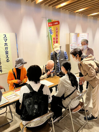 体験ブースの様子：２人の人にボイスオーバーについて説明している写真